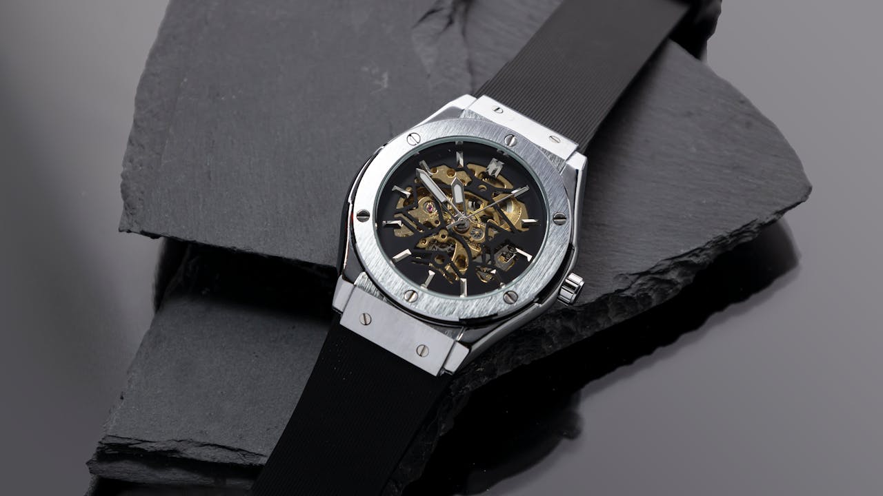 Home Close-up of a skeleton dial wristwatch displayed on a sleek slate surface, showcasing intricate mechanical details.